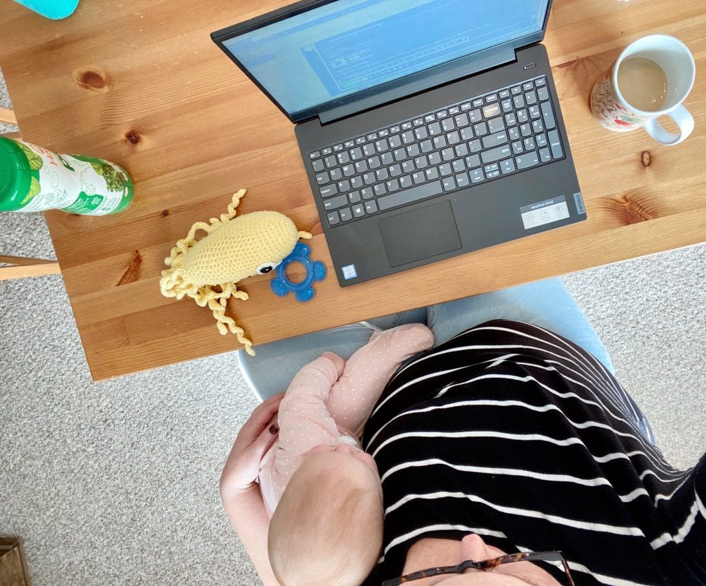 Woman seated at a computer with a baby in her lap