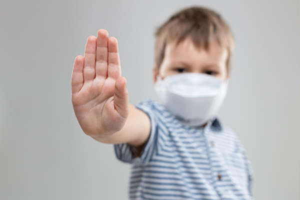 boy in mask gestures stop