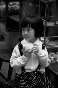 young girl in a school uniform holding a white mug.