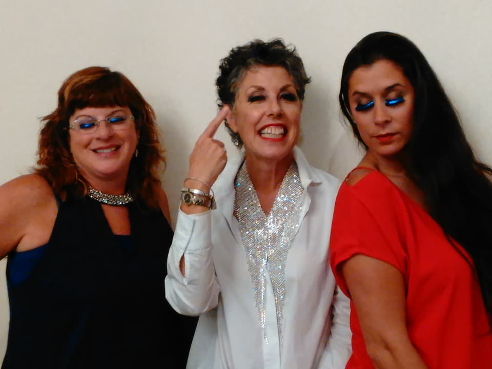 three women wearing makeup and smiling