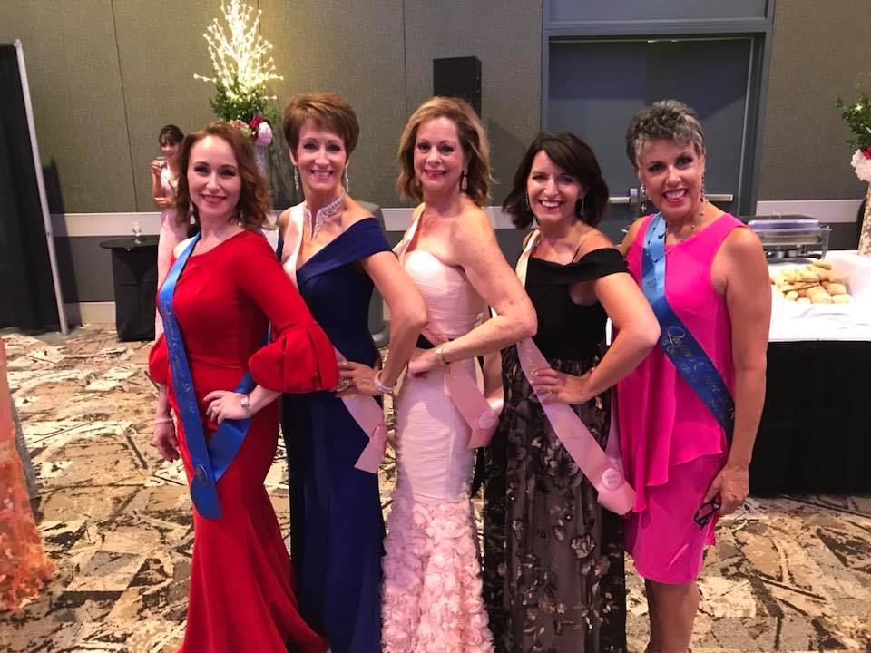 5 women in formal dresses and award sashes