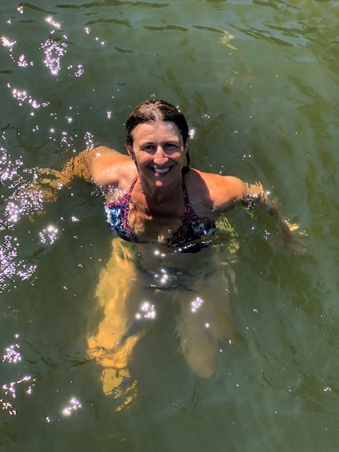 Woman with a big smile, wearing a bikini treading water.
