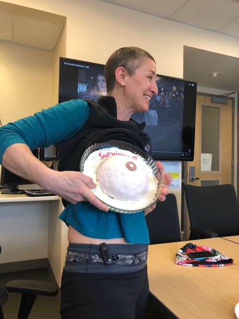 Woman holds breast cake up to chest