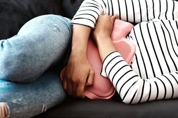 woman holding a hot water bottle on her stomach for cramping