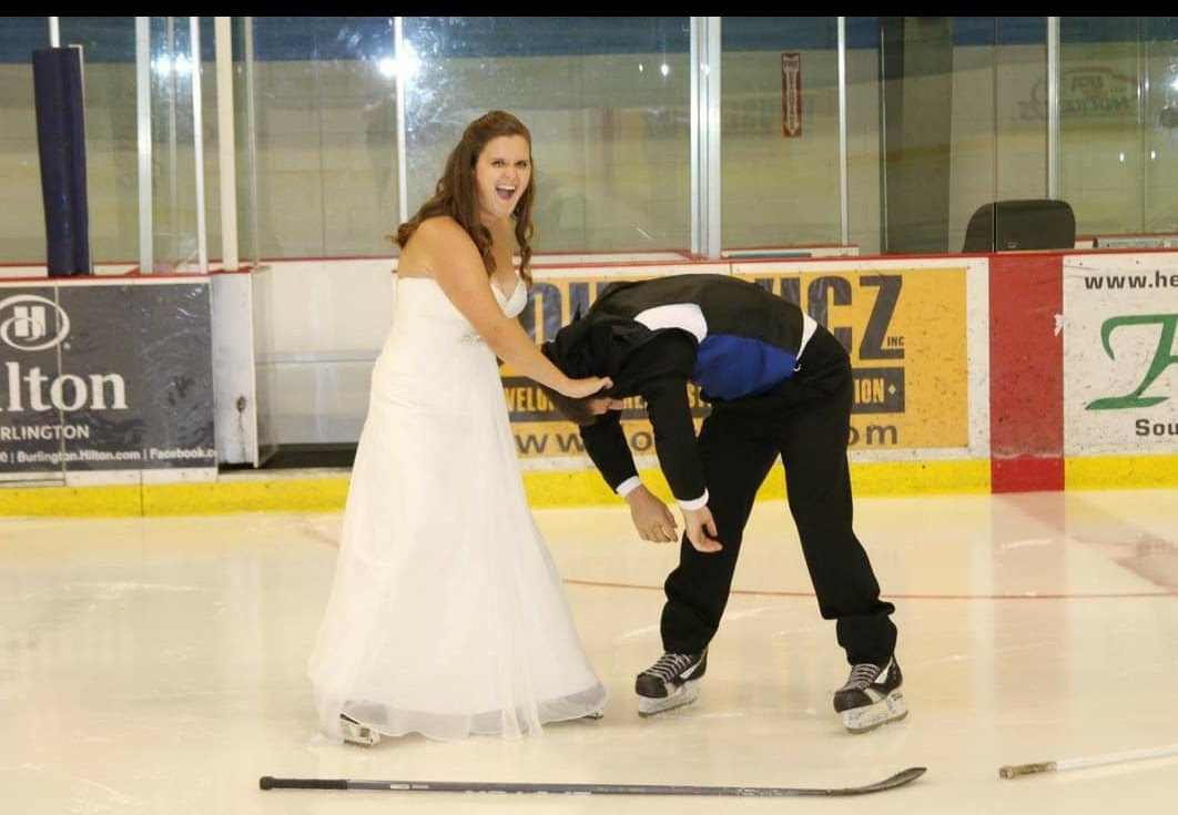 bride and groom wearing hockey skates in a rink