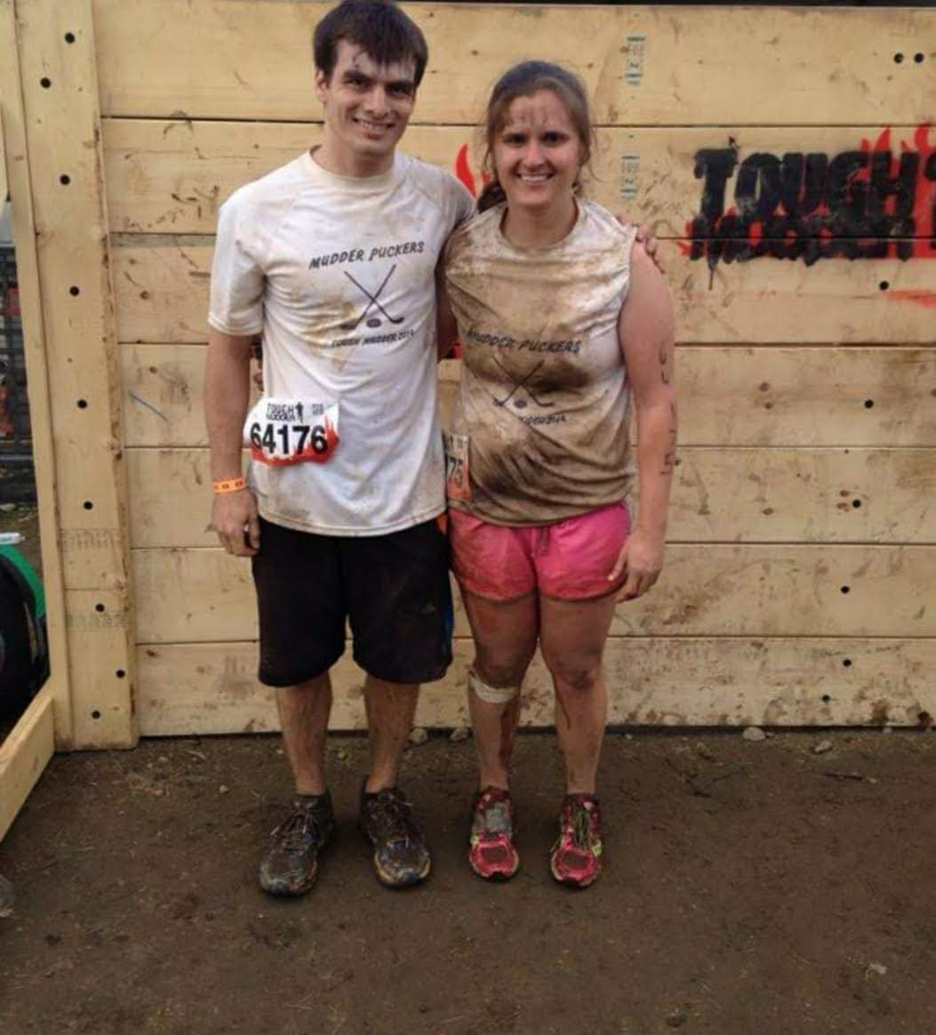 man and woman in running clothes, dirty from completing race