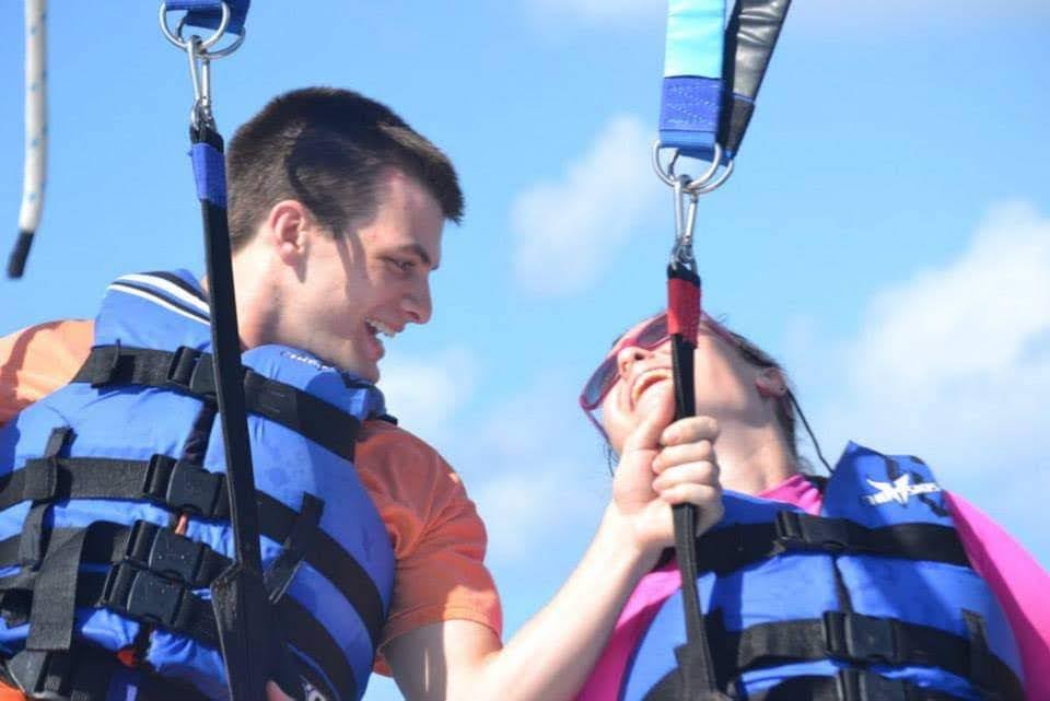 Man and women smiling and laughing at each other while in blue lifejackets and a harness
