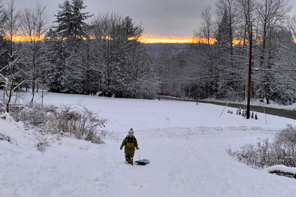 child pulling a sled up a hill in the winter