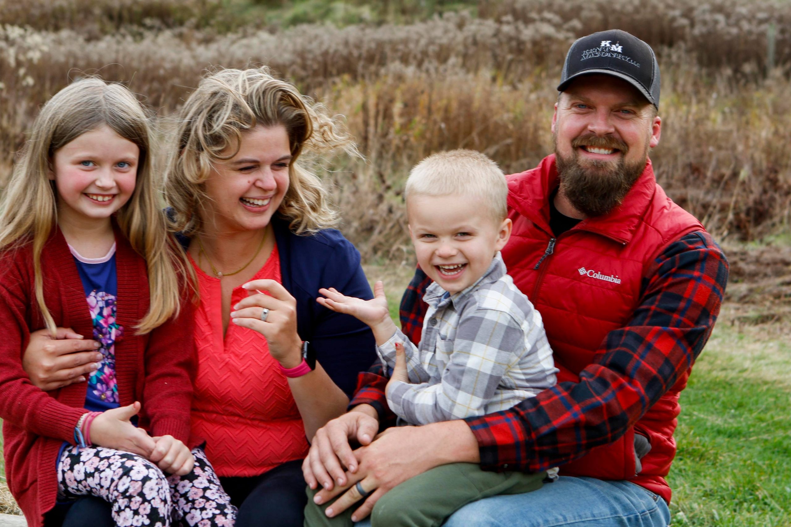 family wearing red outdoors. EVeryone is smiling.