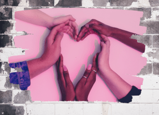 My Kids Taught Me How to Love Valentine’s Day Women's hand form a heart on a pink background in an expression of love.