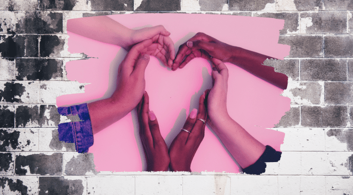 My Kids Taught Me How to Love Valentine’s Day Women's hand form a heart on a pink background in an expression of love.