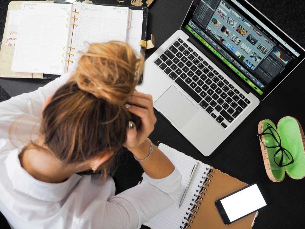 Woman working at a computer, head in hands