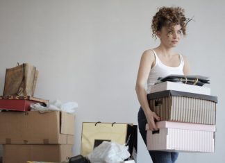I’m a Mess: Learning the Difference Between Decluttering and Tidying Up woman carrying boxes away from a pile