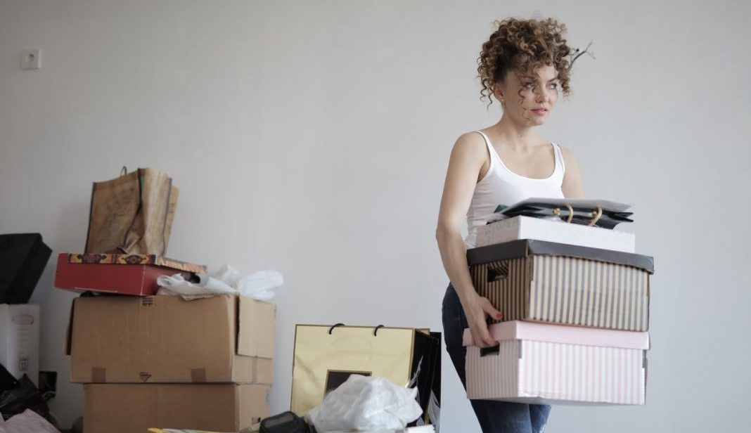 woman carrying boxes away from a pile