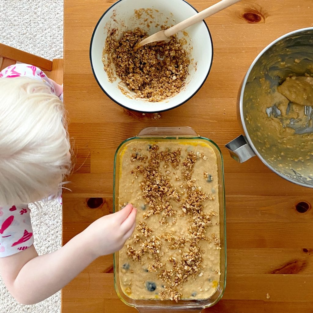 viewed from above: a child sprinkles topping on muffin batter