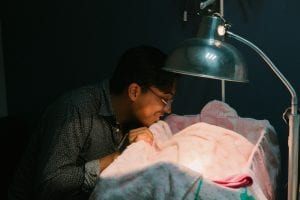 person gazing adoringly at a baby in a hospital crib