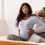 Pregnant lady suffering from backache, husband massaging her shoulders