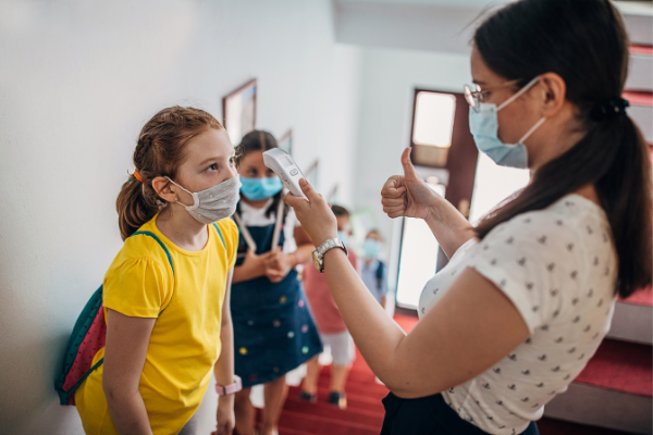 Teacher in mask takes student's temperature