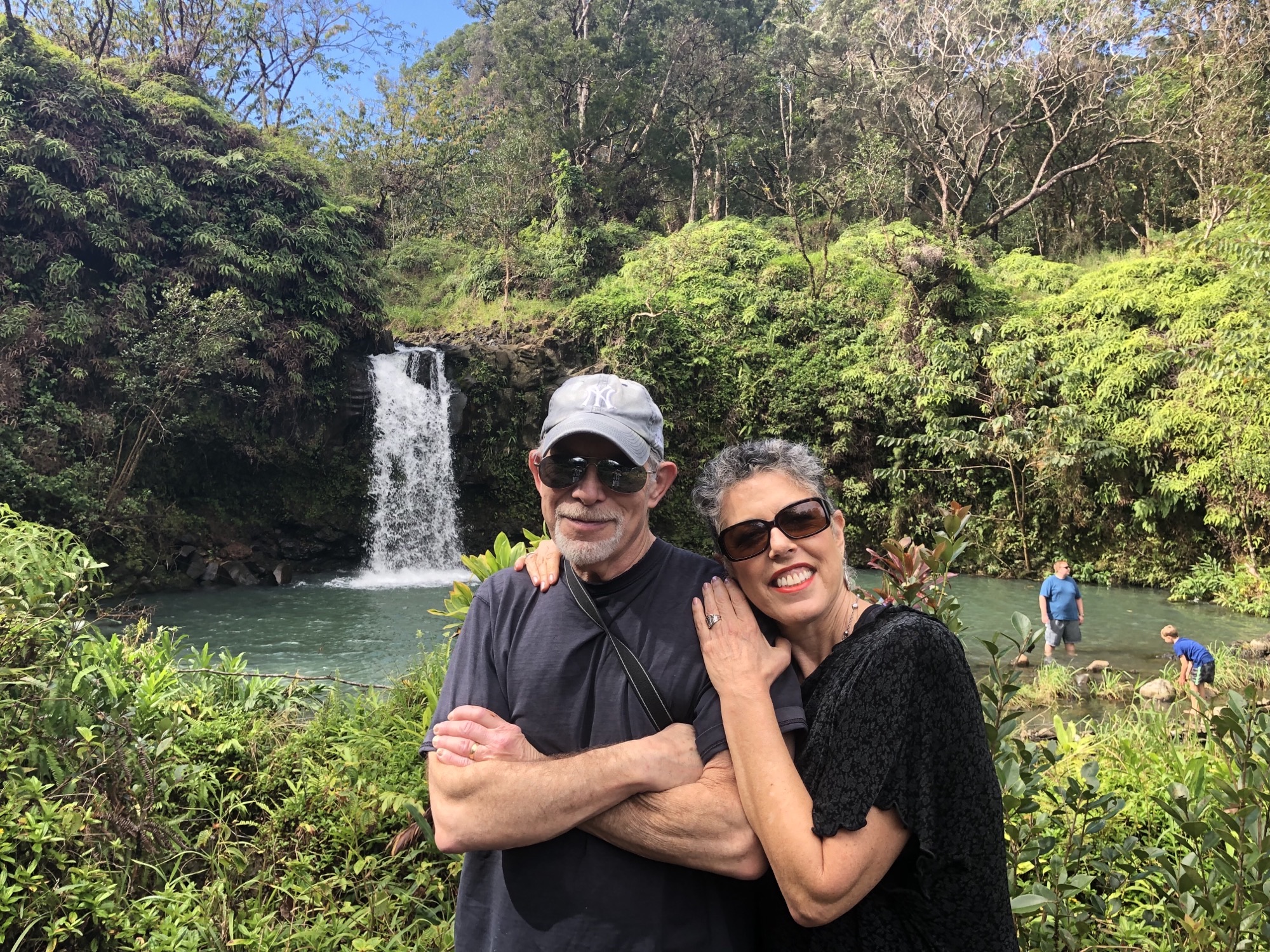 husband and wife in front of a small waterfall