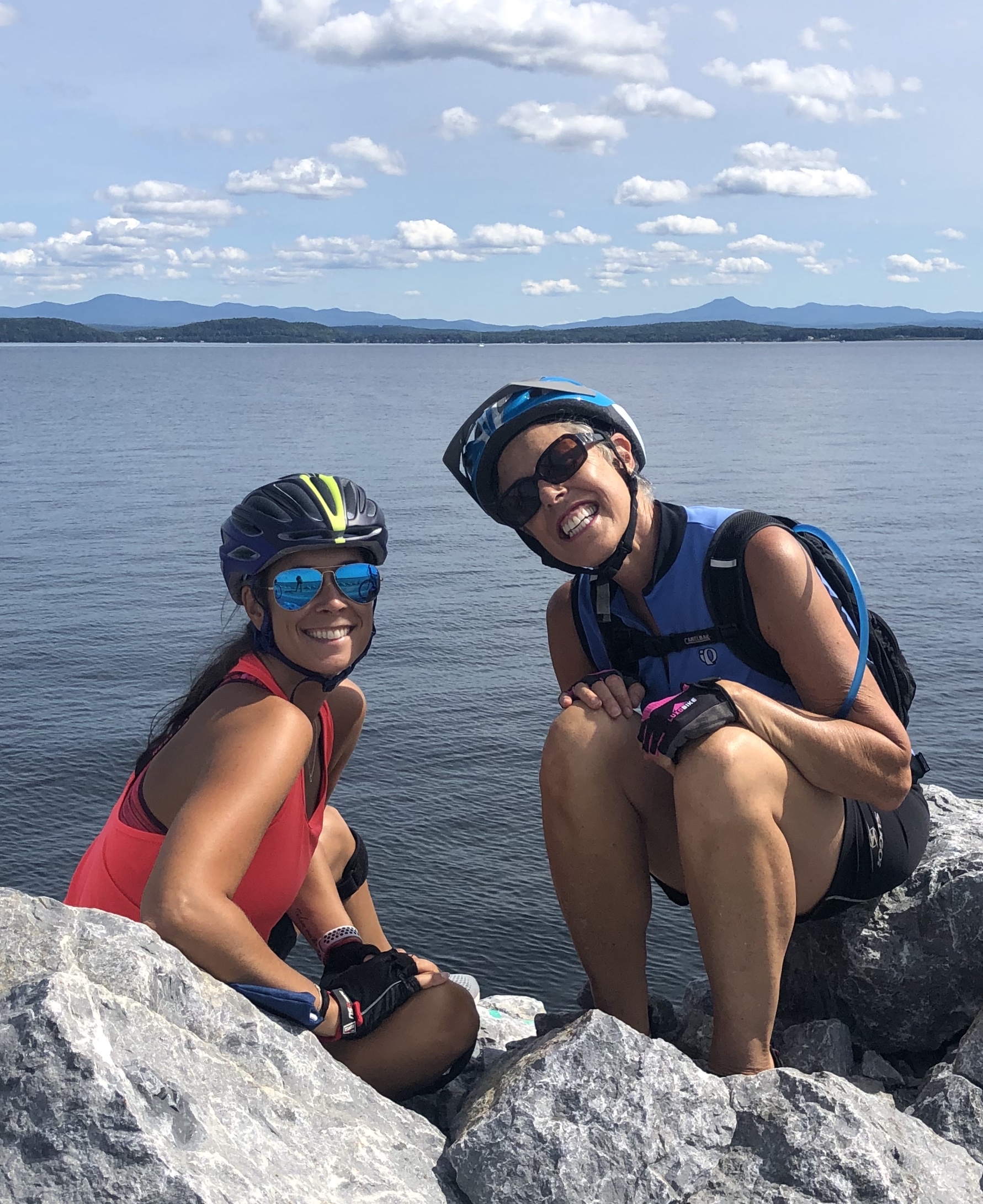 mother and daughter sitting on rocks by the lake