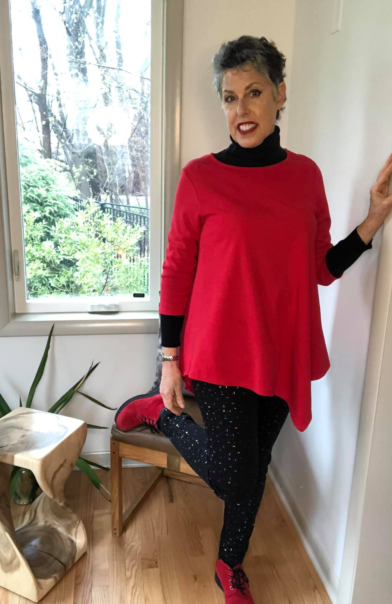 woman in a red top, black pants, and red shoes
