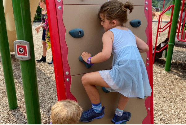 young girl climbing a structure at a playground