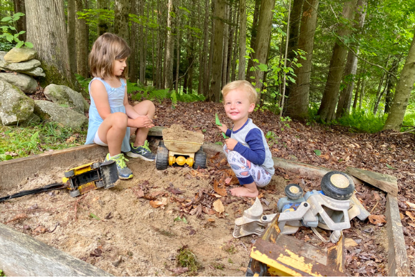 young kids outdoors playing in a sandbox