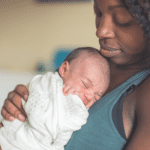 Black woman holds infant tenderly