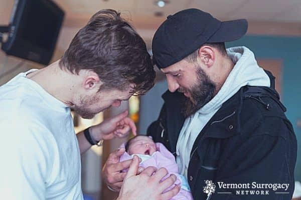 two men cradling a newborn
