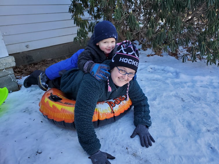 mom on a sled with a toddler on her back