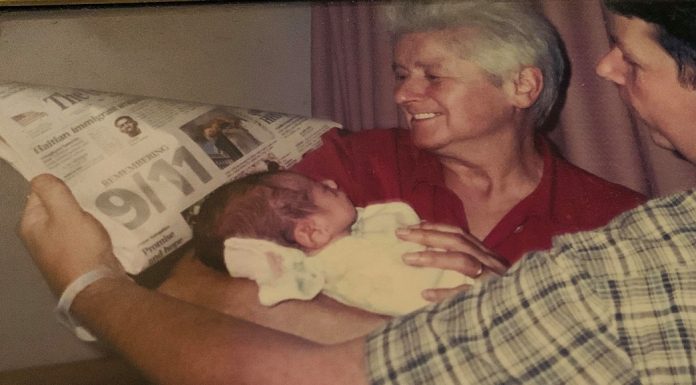 My Son Was Born on September 11 An older woman and young father hold a newborn baby against a newspaper to record the headlines of the day.
