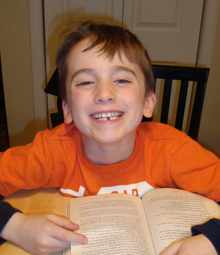 boy smiles at the camera showing a missing tooth