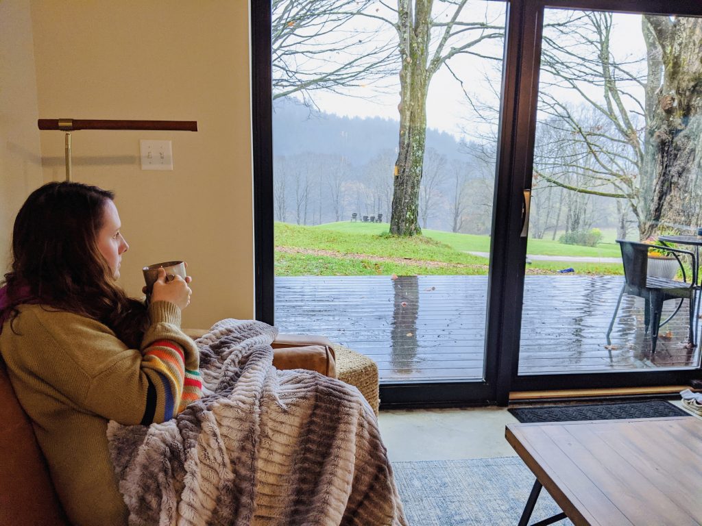 woman drinking from a mug and looking out the window
