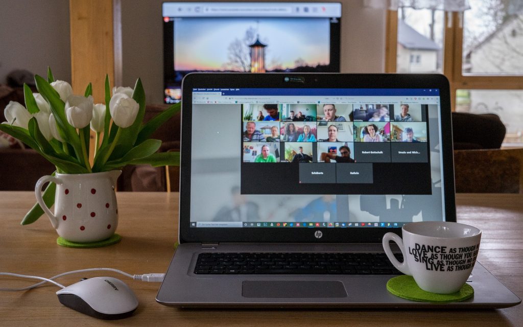 Zoom Meeting on Computer with teacup and vase of flowers on desk nearby