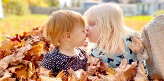 Why We’re Opting Out of Family Portraits two children sitting in a pile of leaves, one gives the other a peck on the nose
