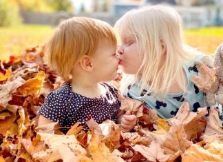 Why We’re Opting Out of Family Portraits two children sitting in a pile of leaves, one gives the other a peck on the nose