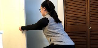 Exercising After Having a Baby, Part 2: 4-8 Weeks Postpartum Woman squats using a door to brace herself