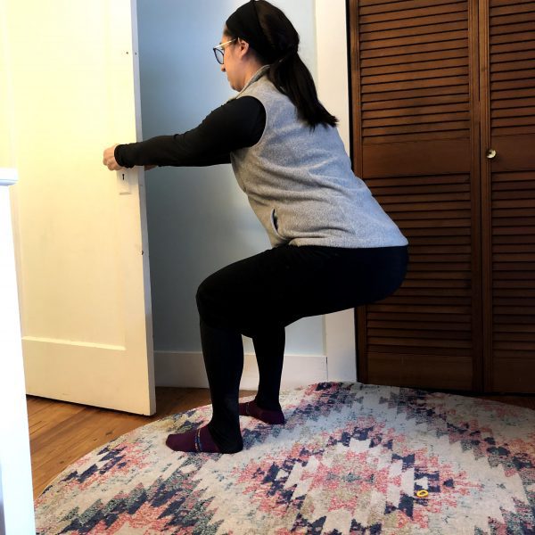 Door Squats Woman squats using a door to brace herself