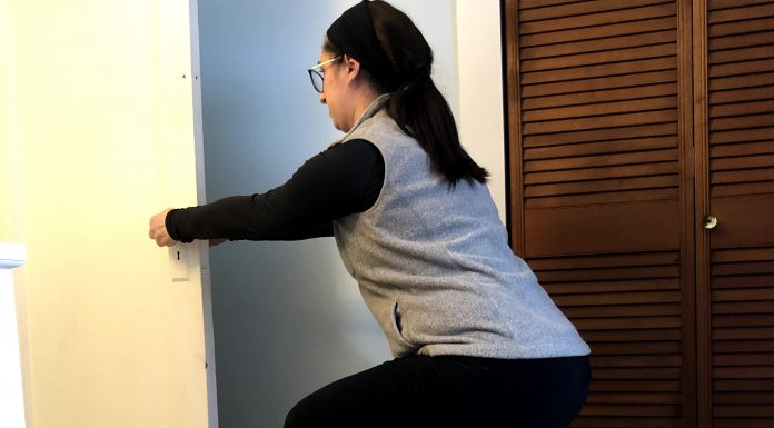 Exercising After Having a Baby, Part 2: 4-8 Weeks Postpartum Woman squats using a door to brace herself