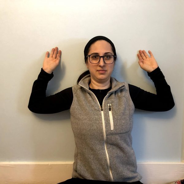 Wall Slides Woman does arm exercises against a wall