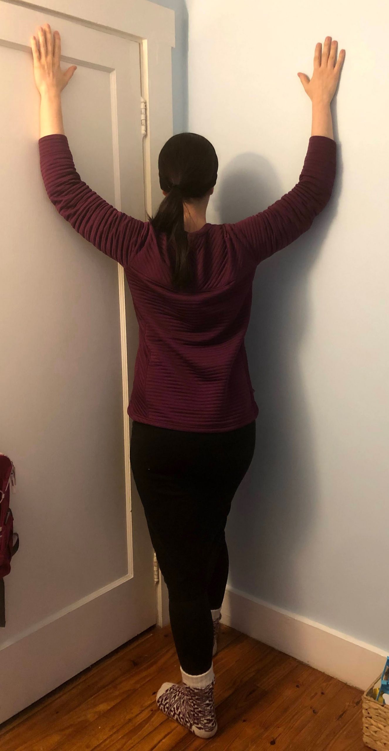 Corner Pec Stretch woman does a pec stretch in the corner of a room