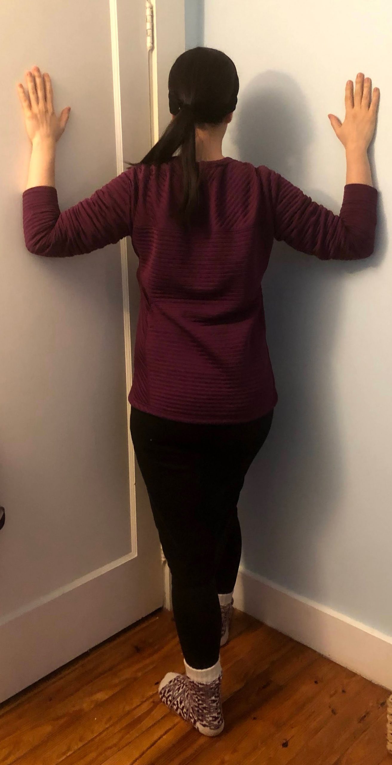 Corner Pec Stretch woman does a pec stretch while leaning into the corner of a room