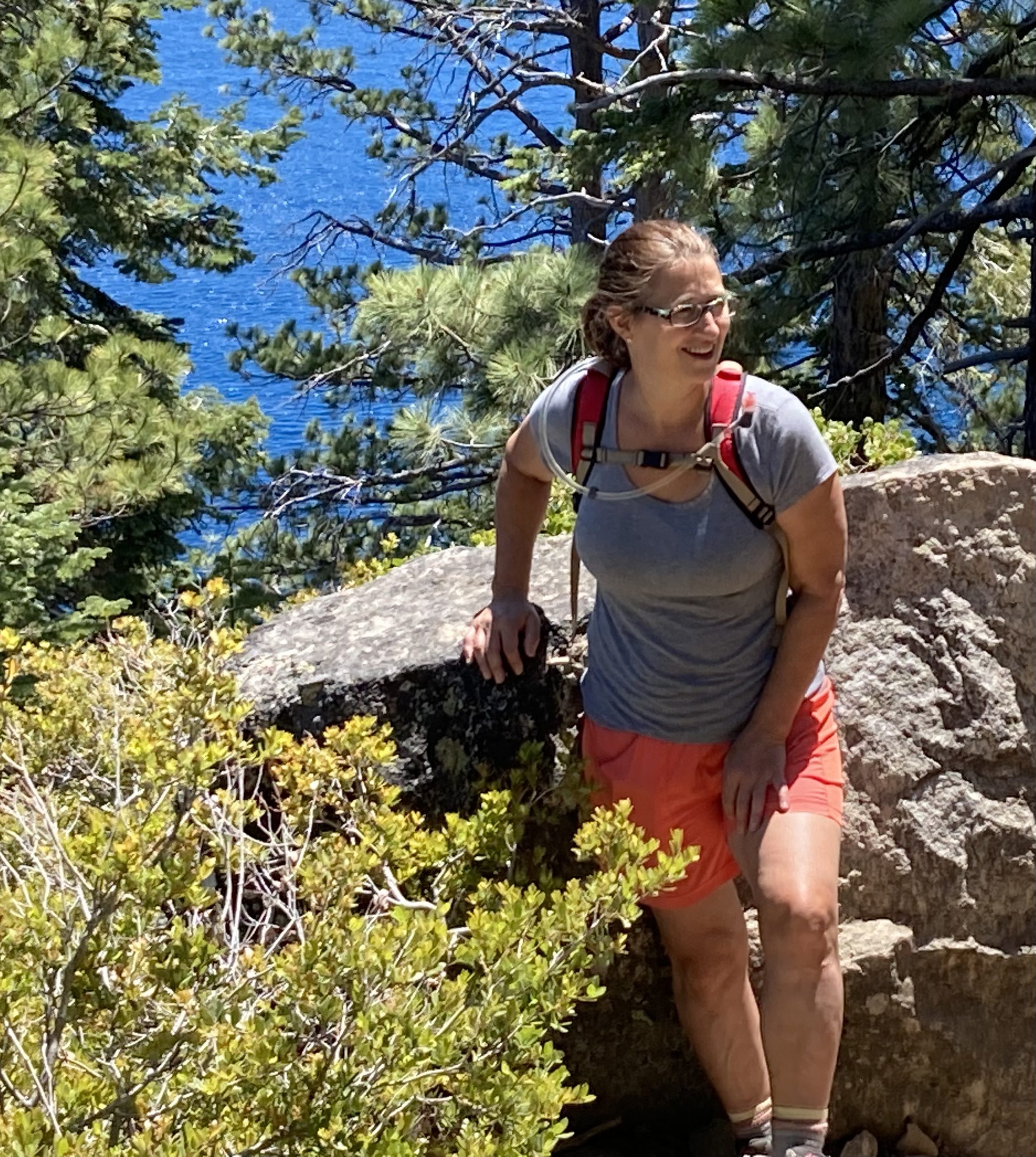 woman on a hike, leaning against a boulder