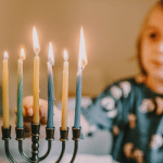 child lighting a menorah