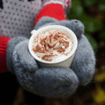 cup of hot chocolate held in mittens