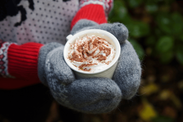 cup of hot chocolate held in mittens