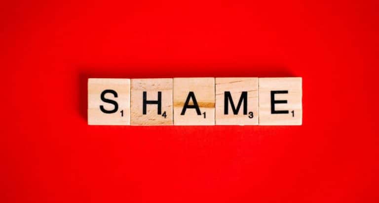 Scrabble letters spelling the word "shame" on a red background.