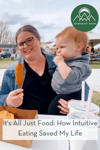Woman smiles at the camera while holding food in one hand with her baby in her other arm