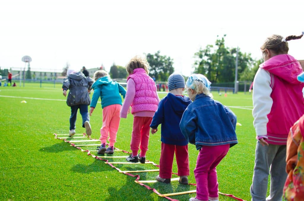 children jumping outside on a grass ladder