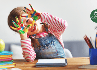 Preschool-aged girl smiling with paint on her hands